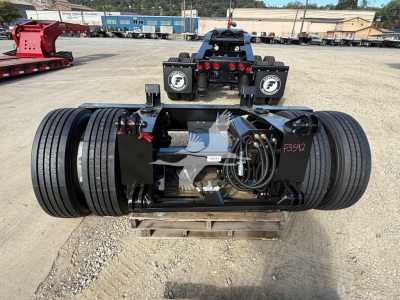 Fontaine flip axle trailer rear view showing heavy duty axles, dual wheel assemblies, and hydraulic connections mounted on a black frame with wiring and fittings.