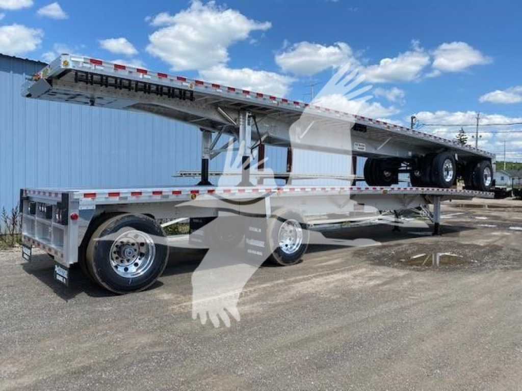 Flatbed trailer with a raised upper deck on a Reitnouer Big Bubba, tandem axles, chrome wheels, and reflective tape along sides.
