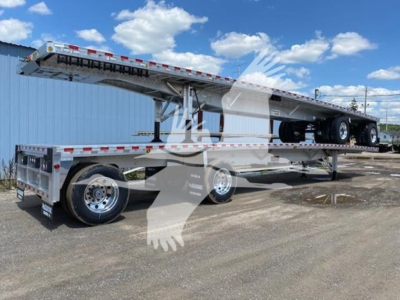 Flatbed trailer showing a raised flatbed on a multi-axle chassis with dual rear axles and a long steel deck. Visible wheels, reflective safety tape along edges, and a raised gooseneck portion.