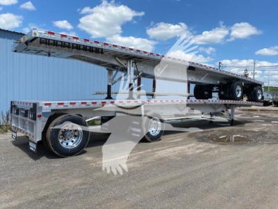 Flatbed trailer with a raised upper deck on a Reitnouer Big Bubba, tandem axles, chrome wheels, and reflective tape along sides.