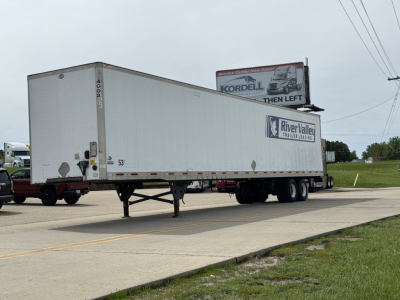 Trailer with River Valley Trailers logo and a Kordell billboard in background. White 53' box trailer on dual rear axles, front landing gear visible. Side text shows 53'.