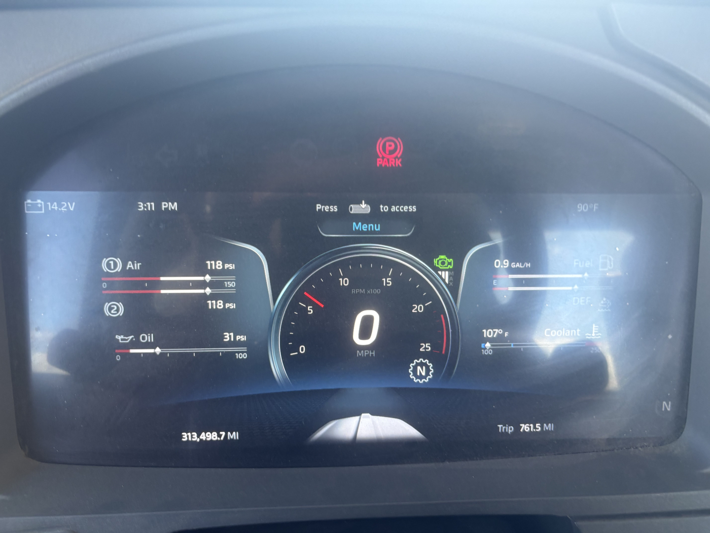 Digital instrument cluster of a 2024 Kenworth T680 showing gauges and readouts. Center digital speedometer at 0 mph, left fuel, air, oil indicators; right coolant temp; bottom odometer shows 313,498.7 mi and trip 761.5 mi.