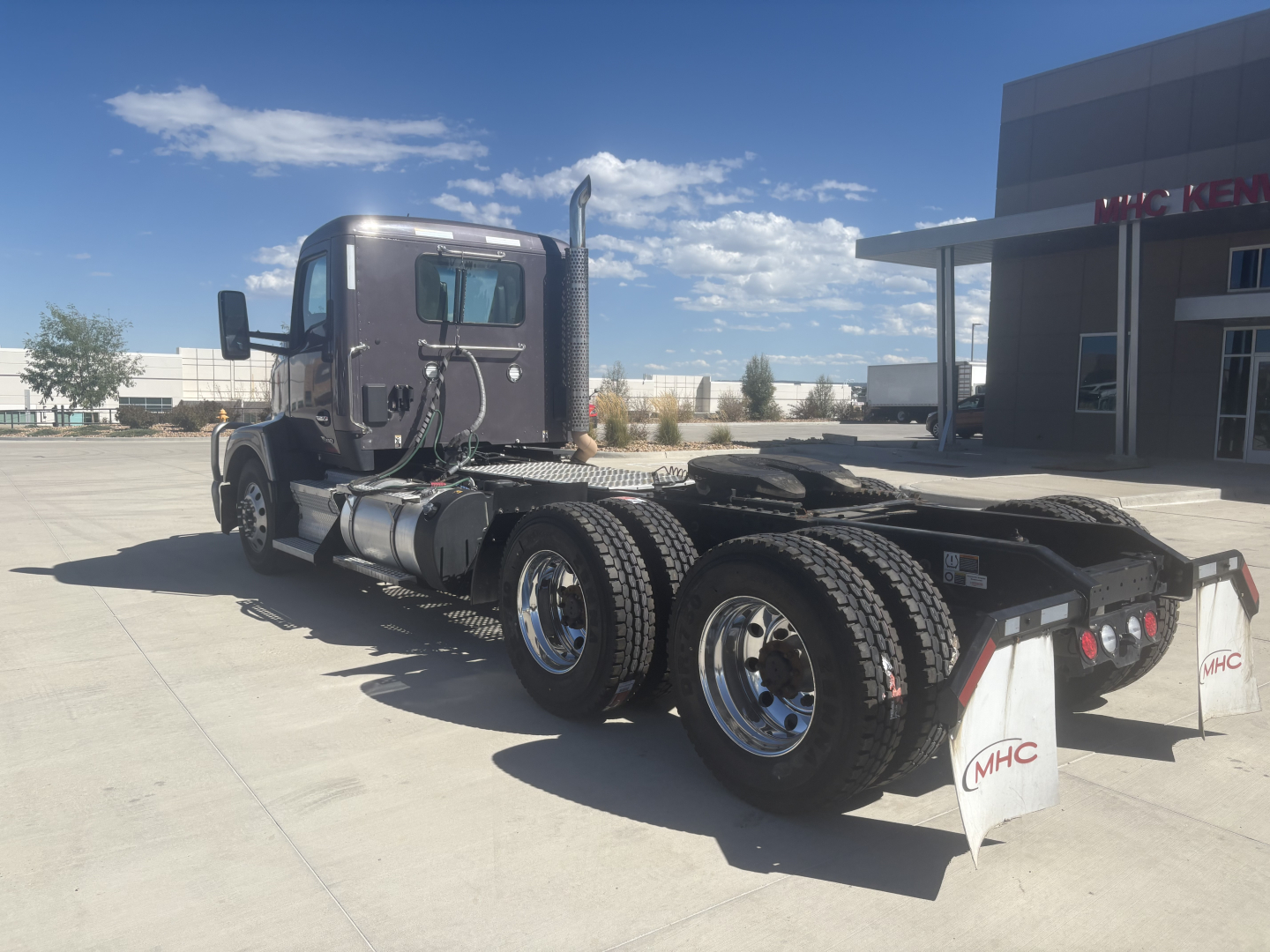 Kenworth T680 conventional daycab truck rear view showing fuel tanks and triple rear axles