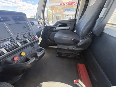 Kenworth T680 truck interior front cab view showing driver seat, dashboard controls, and window with dealership outside