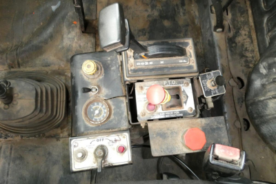 Truck cockpit control panel showing ignition switch, dashboard switches, red emergency stop, and gear selector with labels; Mack RD688S interior components visible.