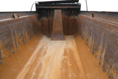 Dump truck bed insides showing rust and dirt with tailgate area; empty cargo space of a 2000 Mack RD688S.
