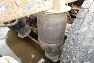 Air spring and undercarriage of a Mack RD688S dump truck showing air suspension air bag and adjacent tire.