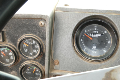 Dashboard gauges in a Mack RD688S dump truck showing tachometer and air pressure gauges with dirt on panels.