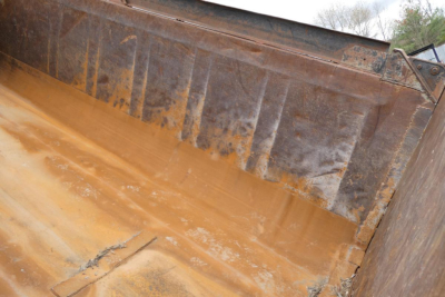 Mack RD688S dump truck bed showing rust-stained steel with dirt and wear.
