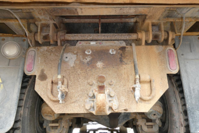 Rear view of a Mack RD688S dump truck undercarriage showing the differential housing with rust and two hydraulic lines, axle housings, and taillight recesses.