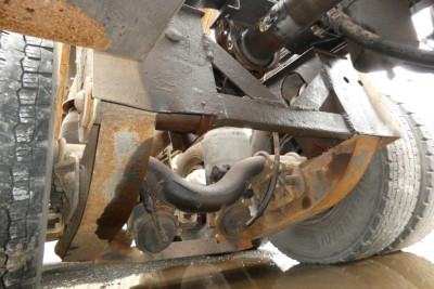Underbody view of a 2000 Mack RD688S dump truck showing suspension and drivetrain components, including a drive shaft, hoses, and frame with some surface rust.