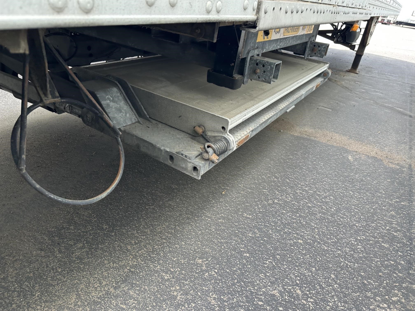 Rear of a used 2015 Utility 3000R trailer showing a folding side step and metal battery box/compartment with cables and brackets.