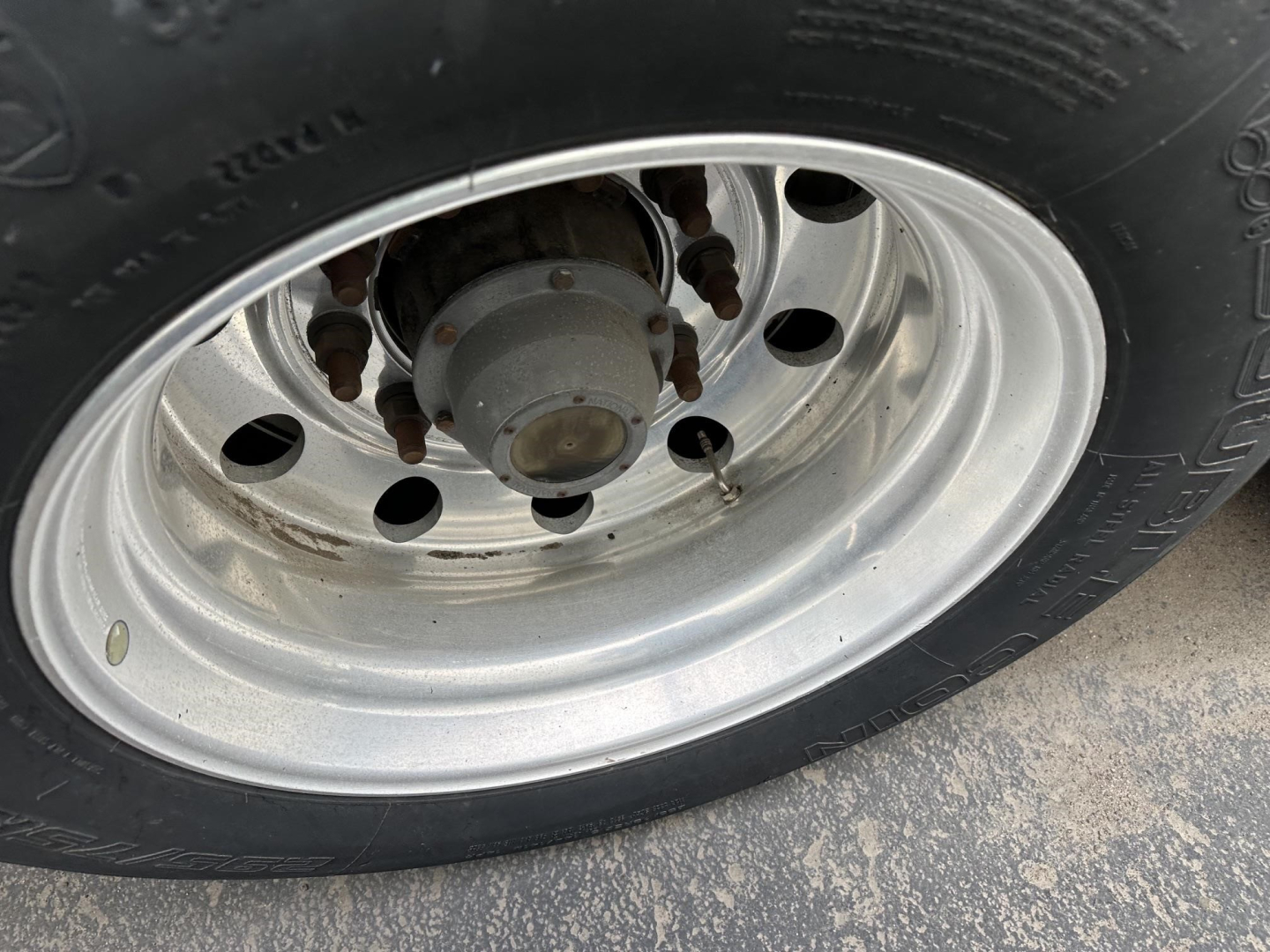 Trailer wheel and tire assembly with stainless steel rim and hub showing on a Utility 3000R trailer.
