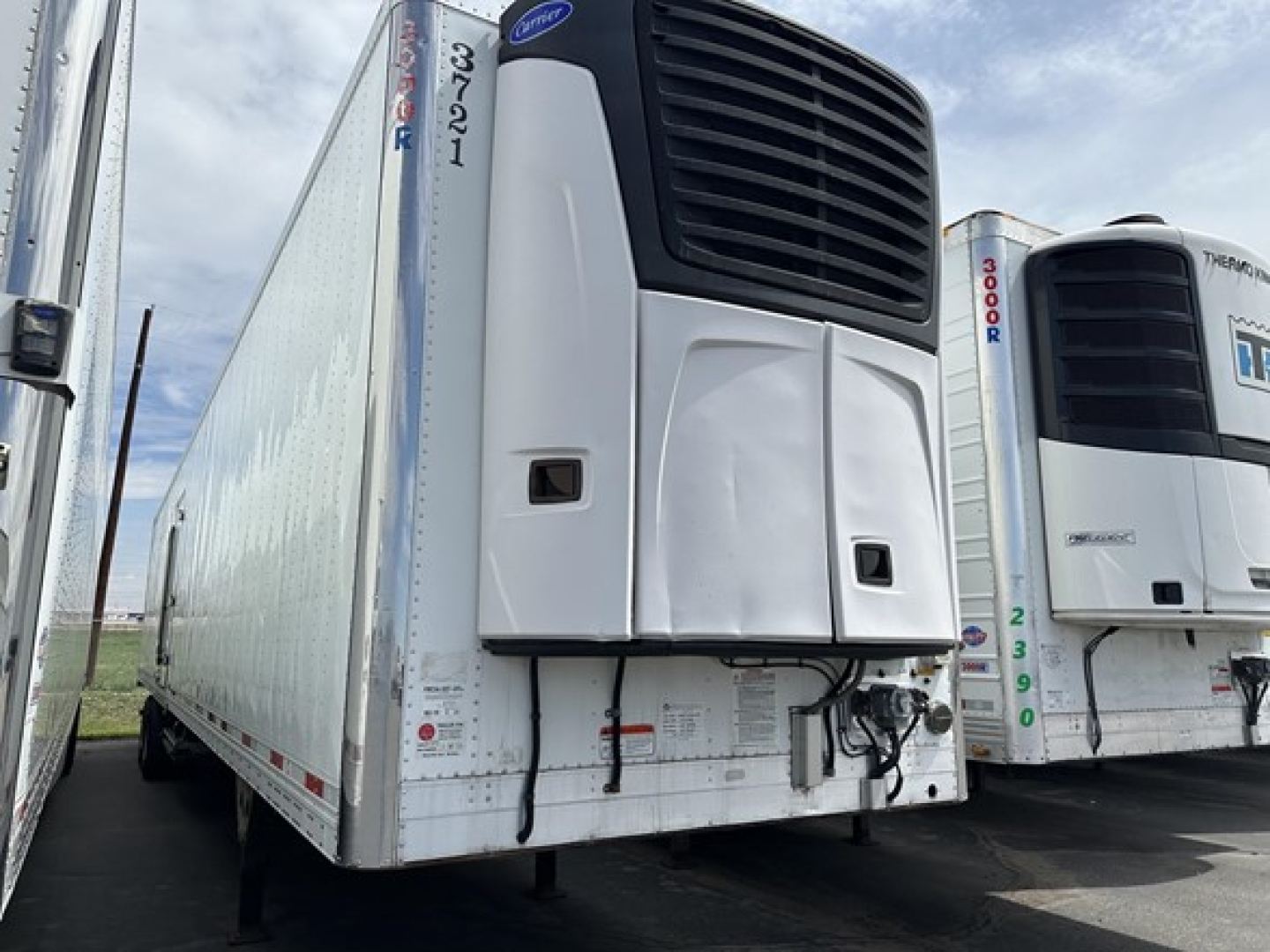 Utility Vector 8600 MT trailer front view showing refrigeration unit and curved nose, with another trailer on the right.