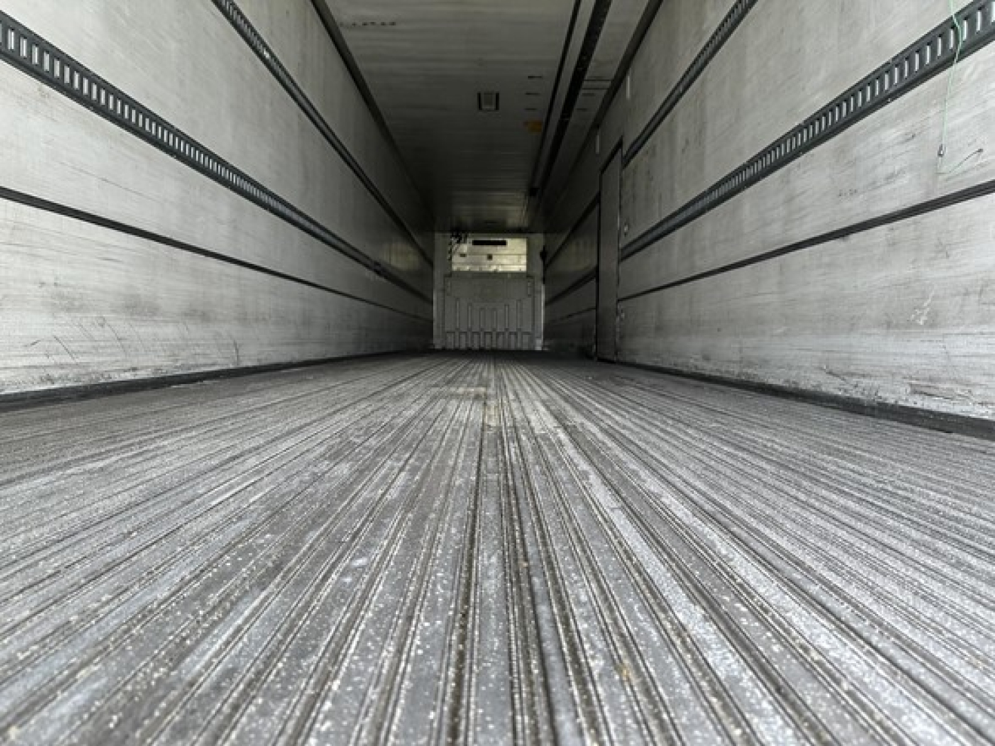 Truck trailer interior showing long ribbed metal floor with side walls and ceiling, empty cargo space in a 53-foot trailer.