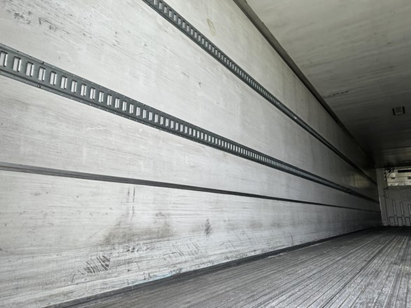 Trailer interior walls with horizontal E-track rails and ribbed floor, empty cargo space in a used 2015 Utility Vector 8600 MT trailer.