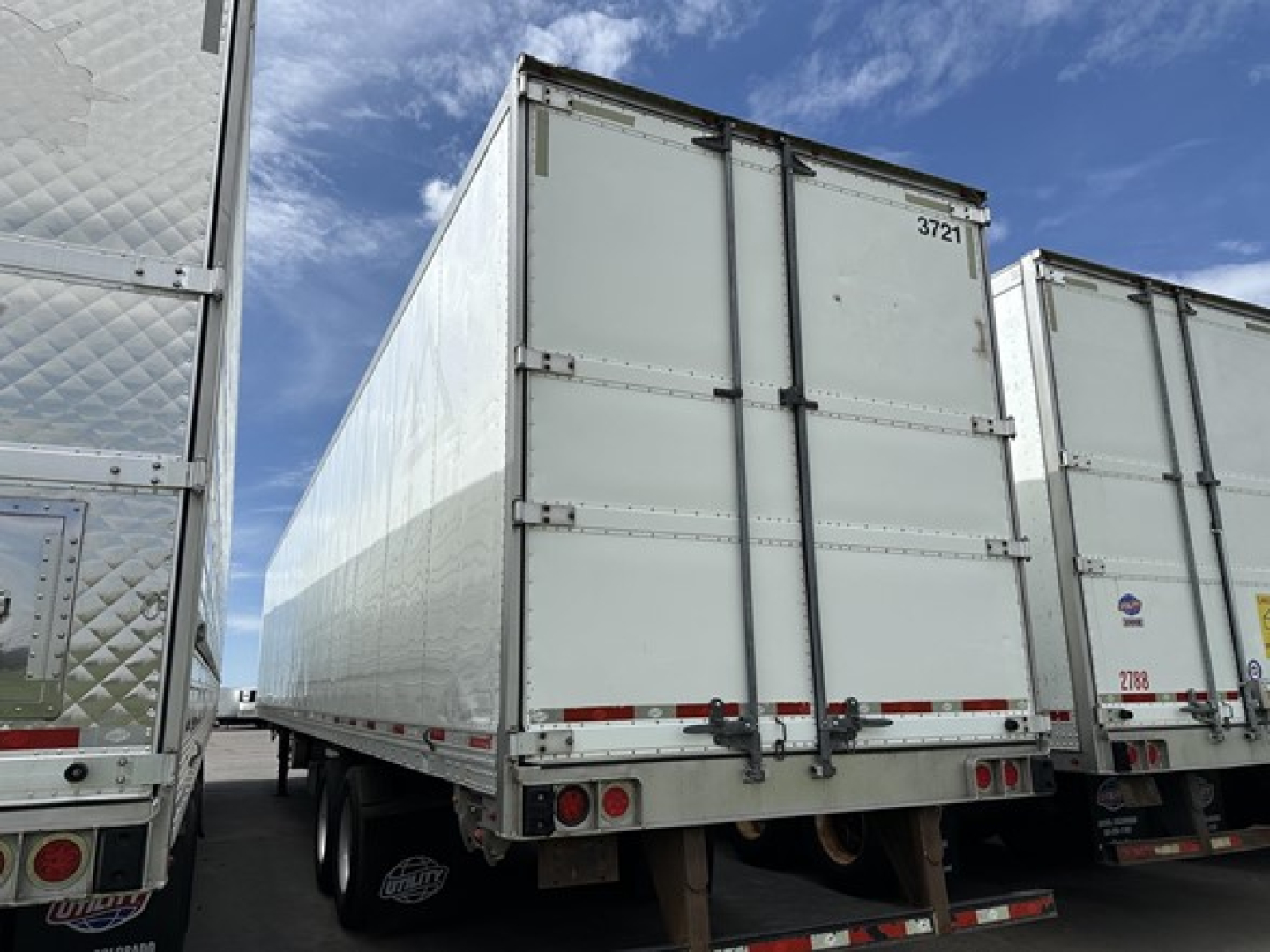Trailer rear view showing white Utility Vector 8600 MT refrigerated trailer with dual rear doors and bumper lights.