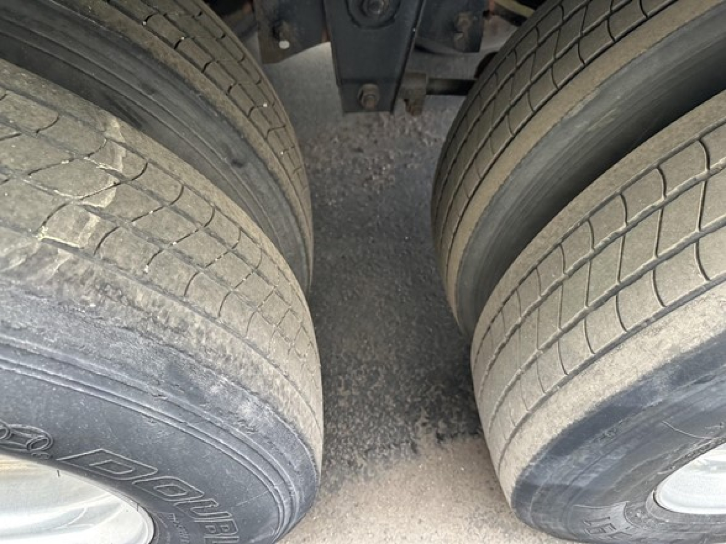 Trailer dual rear wheels with tread detail and mud residue, part of a reefer trailer chassis visible.