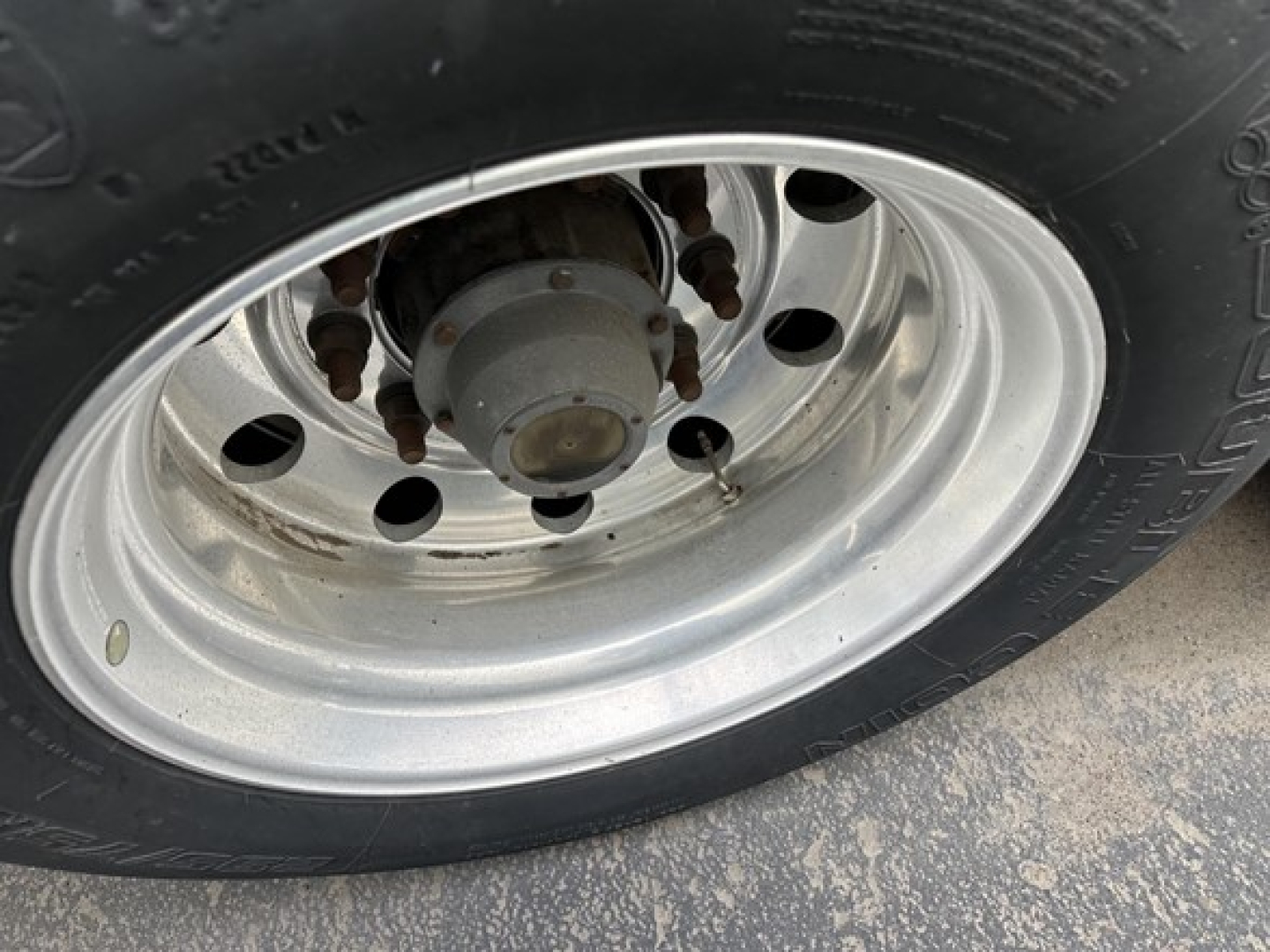 Wheel and tire of trailer showing steel rim, lug nuts, and hub assembly.