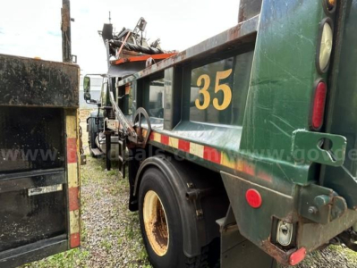 Dump truck side view showing large yellow '35' marking, green body, and wheel well; visible rear chassis and tail light.