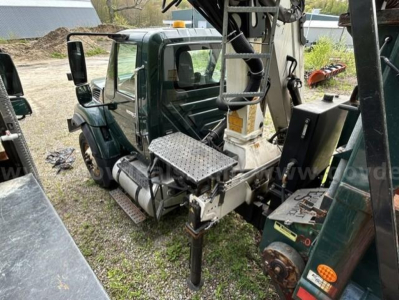 Truck cab and boom crane attachment visible with platform and hydraulic components near the operator area.