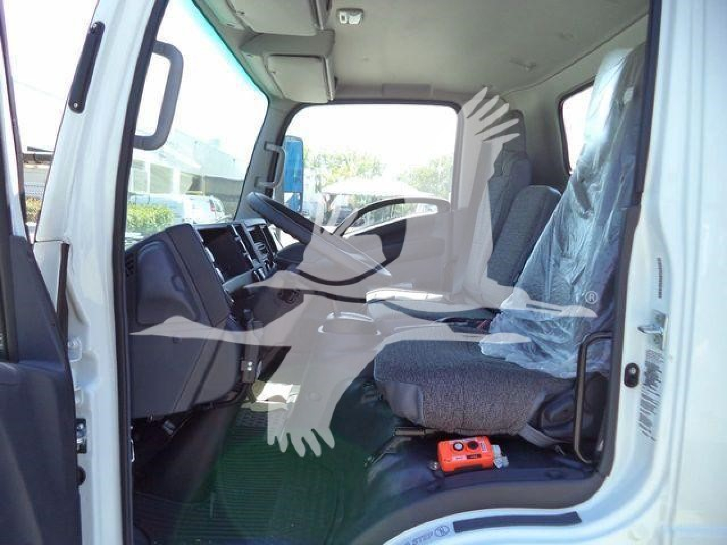 Isuzu NPR-HD truck cab interior with two front seats and dashboard, driver-side door open, plastic seat cover on passenger seat.