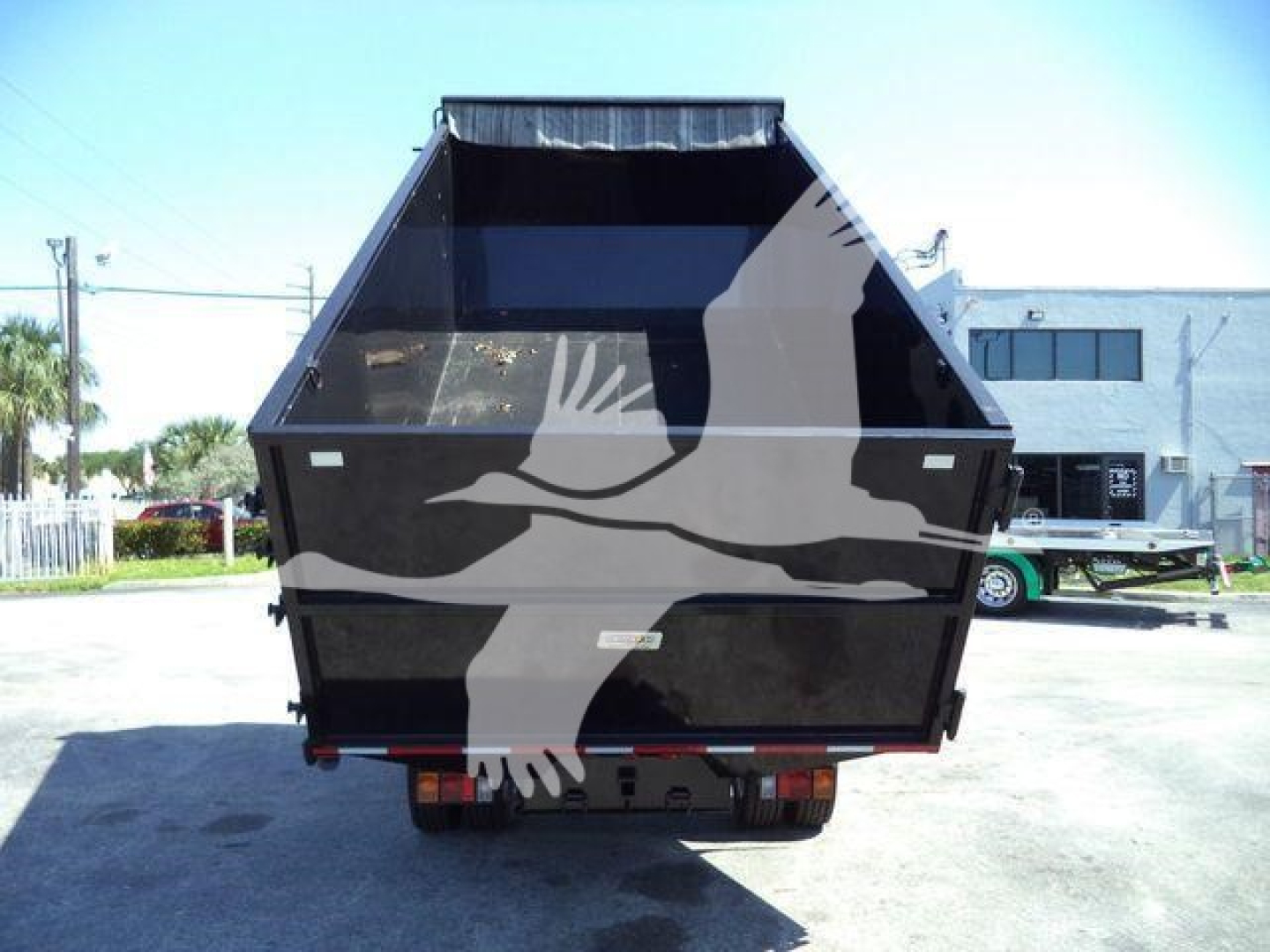 Isuzu NPR-HD dump truck bed seen from rear showing open-top dump bed with black interior and tailgate; indicates used stock number T15005FM.