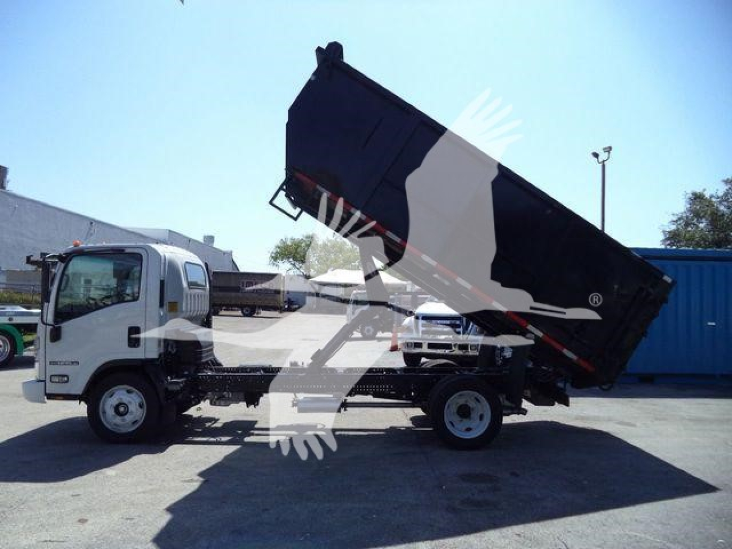 Isuzu NPR-HD dump truck in-service showing cargo bed raised and hydraulic system.