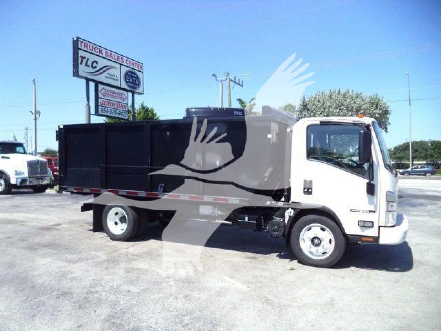 Isuzu NPR HD dump truck shown in a dealership lot, white cab with black dump bed, side view.