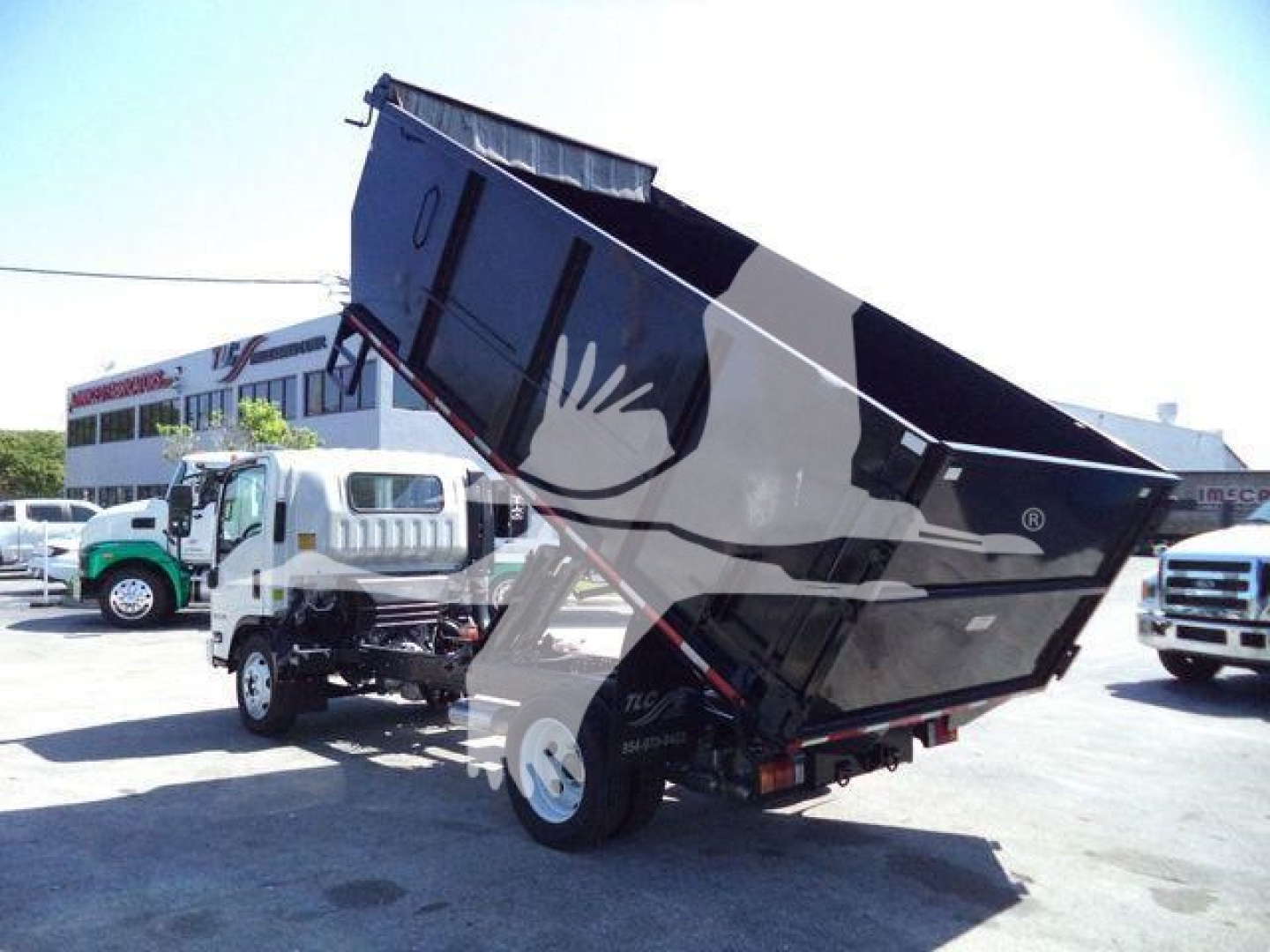 Isuzu NPR HD dump truck with raised bed showing hydraulic lifting mechanism and dark body color.