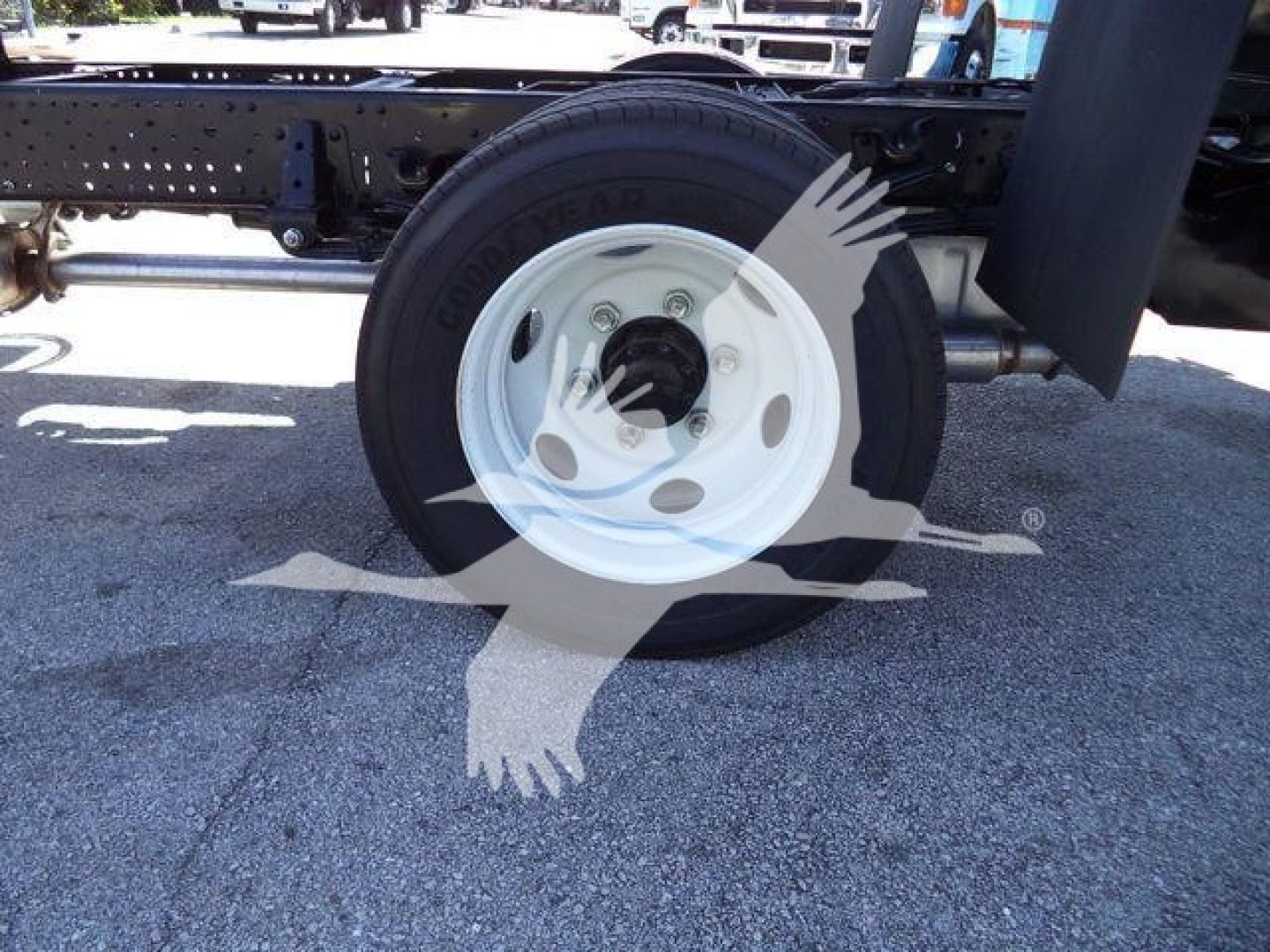 Truck wheel and axle with Goodyear tire and white rim, undercarriage frame visible.