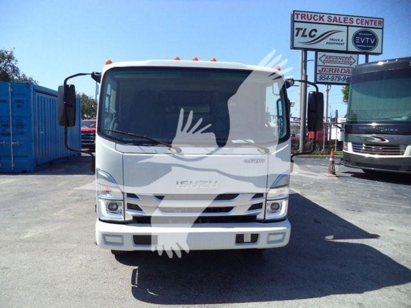 Isuzu NPR-HD truck front view in a dealership lot with signage in background.