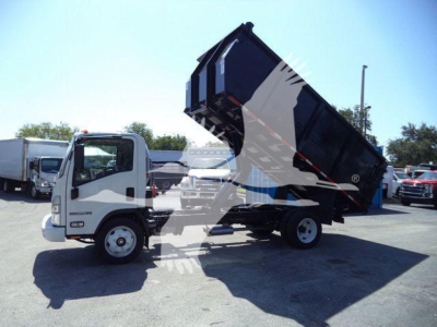 Isuzu NPR-HD dump truck with raised dump bed in a lot