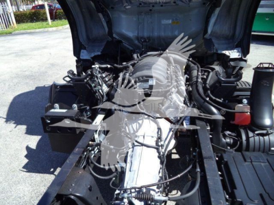 Isuzu NPR HD truck engine bay view with exposed components and wiring under open hood; front frame rails visible.