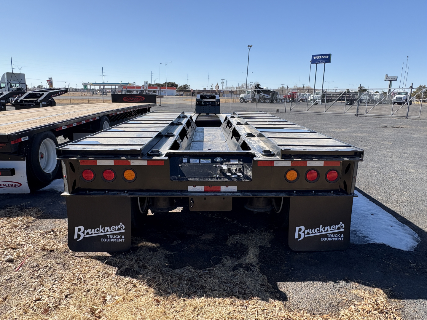 Trailer back view showing Load King 9' wide 24" loading deck trailer with dual axles and dirt/grime on ground