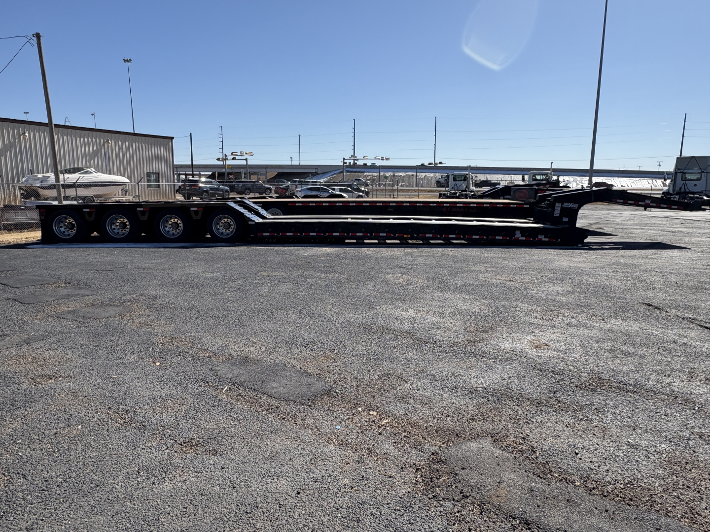 Trailer in a lot showing Load King 554-Quad-9'Wide-24"LDH hydraulic trailer with multiple axles and long lowboy deck visible.
