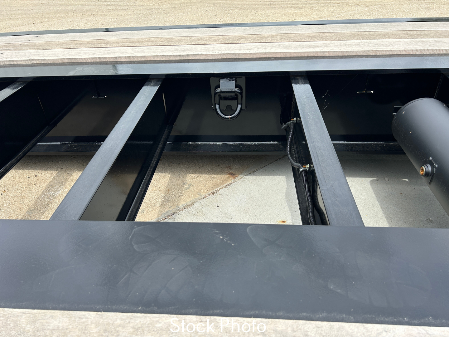 Trailer hinge area of a Load King 554-Quad showing frame beams and storage area with latch mechanism inside.