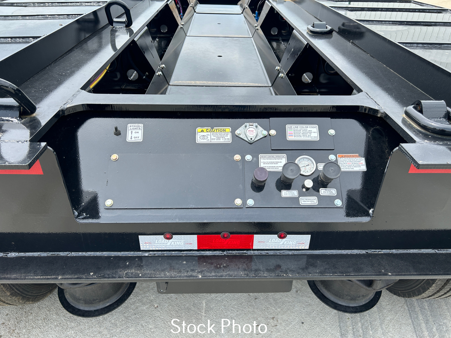 Trailer control panel on Load King lowboy showing gauges, labels, and switches with safety stickers.