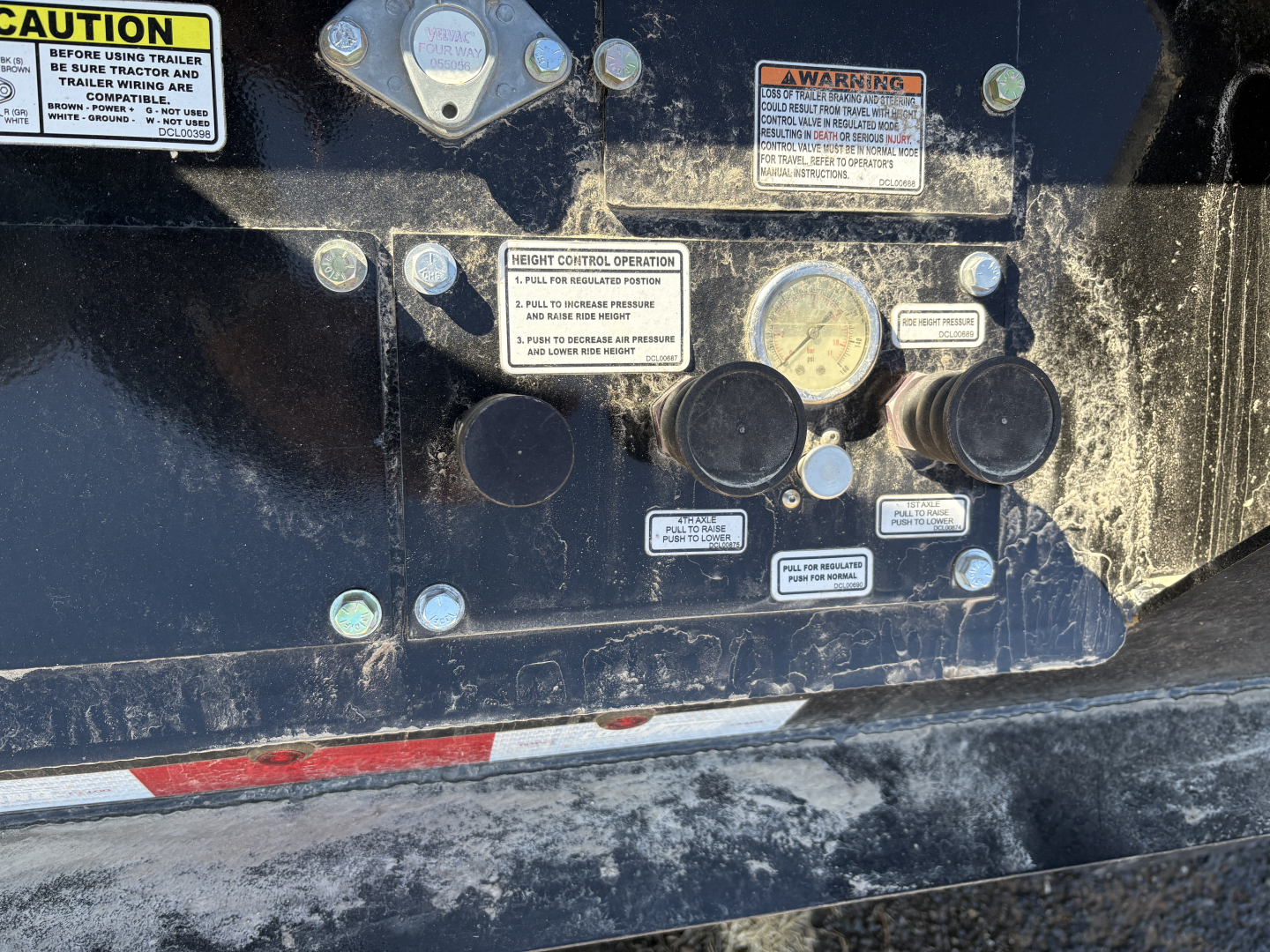 Load King trailer control panel with gauges and warning labels on a black metal surface.