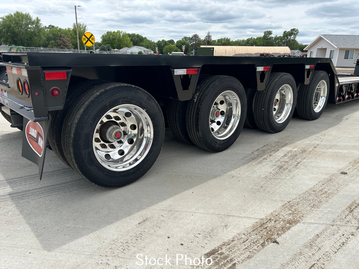 Load King trailer wheels and deck viewed from side showing multiple axles and tires.