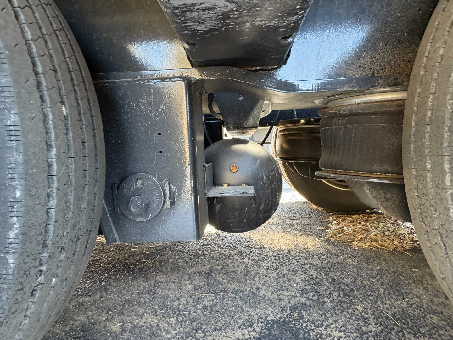 Underbelly of a Load King trailer showing wheels, frame, and suspension components with a round electrical or mechanical cap visible.