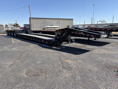 Load King trailer with multiple axles, long lowboy deck in an outdoor lot. Visible text on the trailer includes model features like 554-Quad-9'Wide-24"LDH and general trailer components.