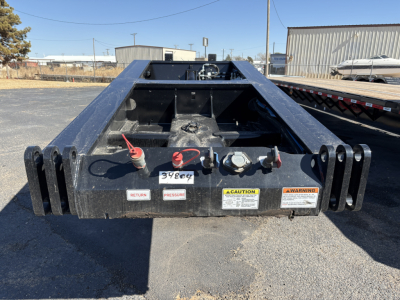 Trailer hitch rear showing hydraulic connections and warning labels on Load King lowboy trailer