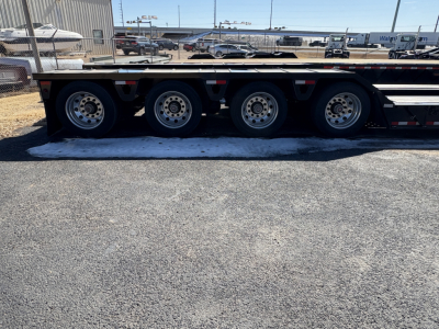 Triple-axle Load King trailer with black deck and silver wheels; no visible text readable on side in this image.