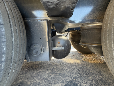 Underbelly of a Load King trailer showing wheels, frame, and suspension components with a round electrical or mechanical cap visible.