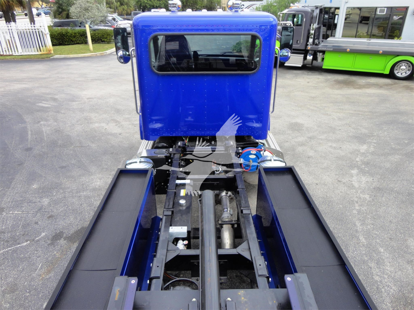 Blue Peterbilt 337 cab over truck seen from behind, with chassis and fifth wheel area visible and two long black side steps.