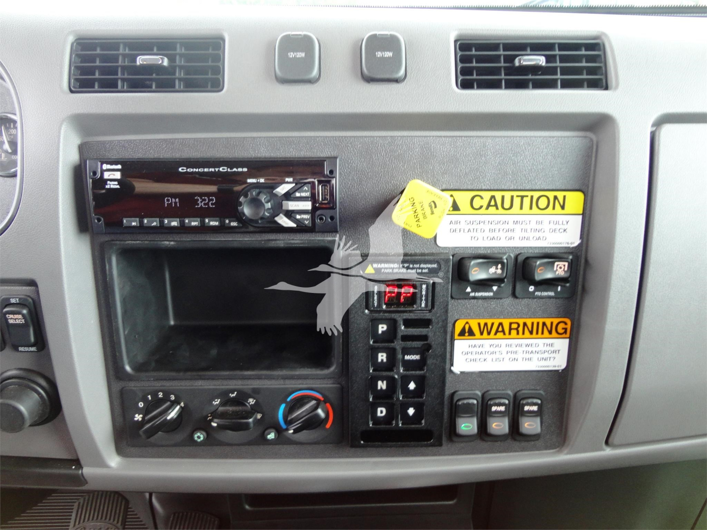 Peterbilt 337 dash area showing aftermarket stereo unit, climate controls, gear selector, and warning labels.