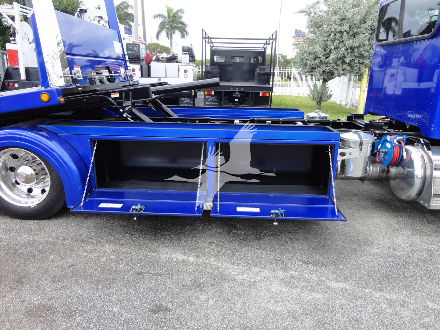 Peterbilt 337 rollback truck bed side compartments open showing tool/storage boxes and hydraulic components.
