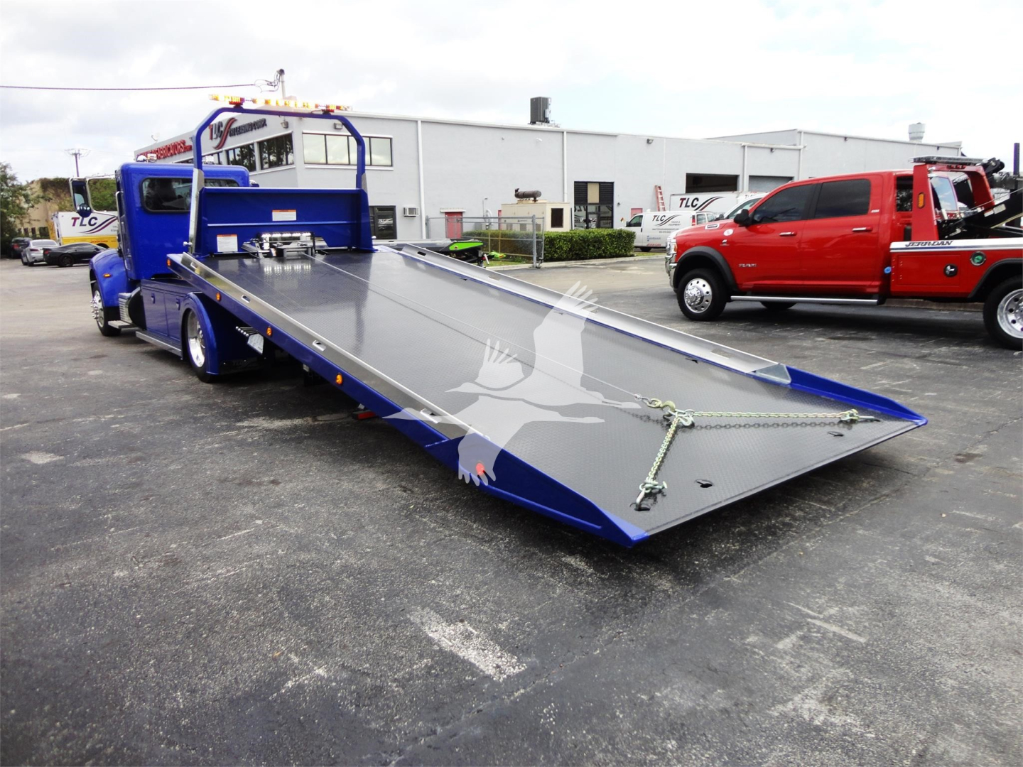Peterbilt 337 rollback truck with a long bed ramp in the open lot.