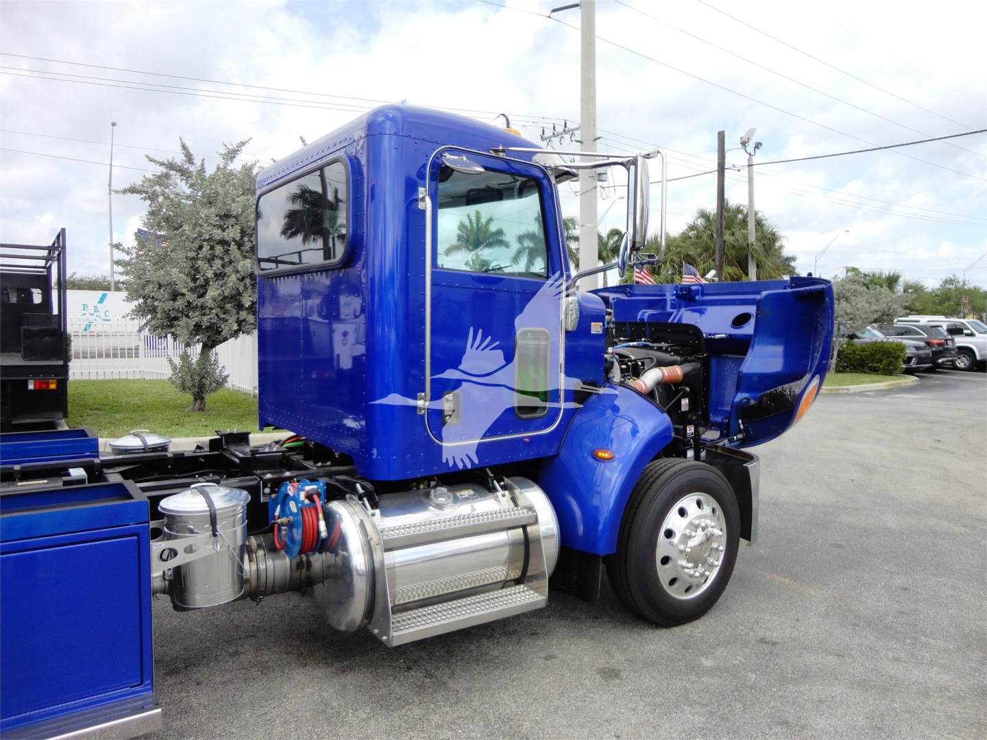 Peterbilt 337 truck with blue cab, engine exposed on the side, fuel tanks and chrome steps visible.